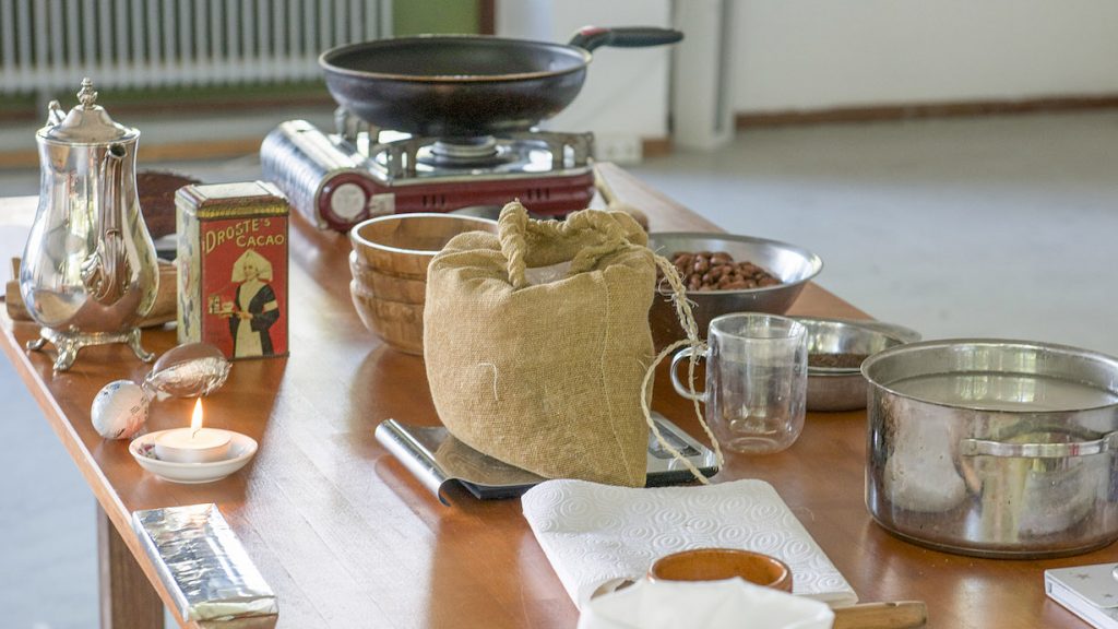 Image description: pans, plates, foods and related materials, poetically positioned on a table.